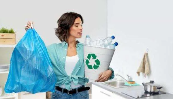 A woman holds a bag and a can full of plastic recycling
